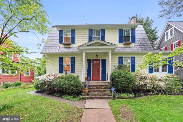 view of front of property with a chimney, a front lawn, and a high end roof