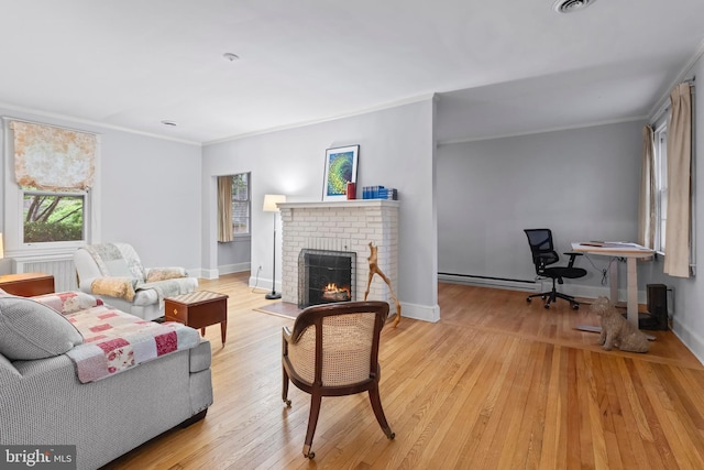 living room with a baseboard heating unit, a fireplace, crown molding, light wood-style flooring, and baseboards
