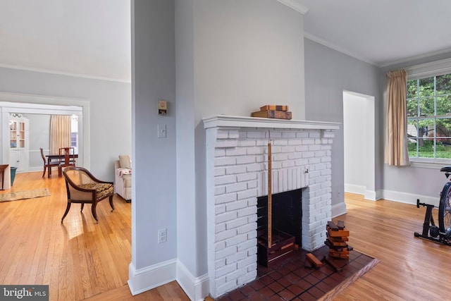 living area featuring wood finished floors, baseboards, ornamental molding, and a fireplace