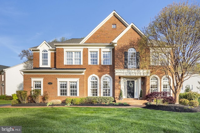 colonial home with brick siding and a front lawn