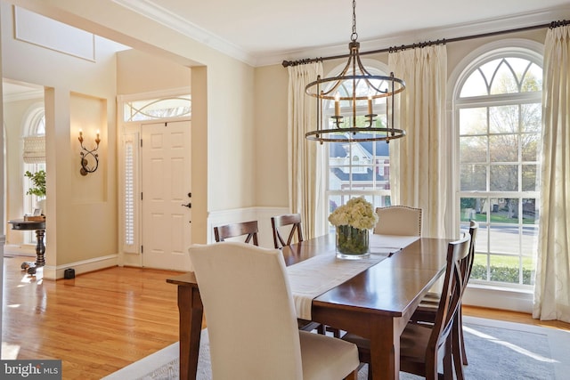 dining area featuring crown molding, a chandelier, a wealth of natural light, and light wood finished floors