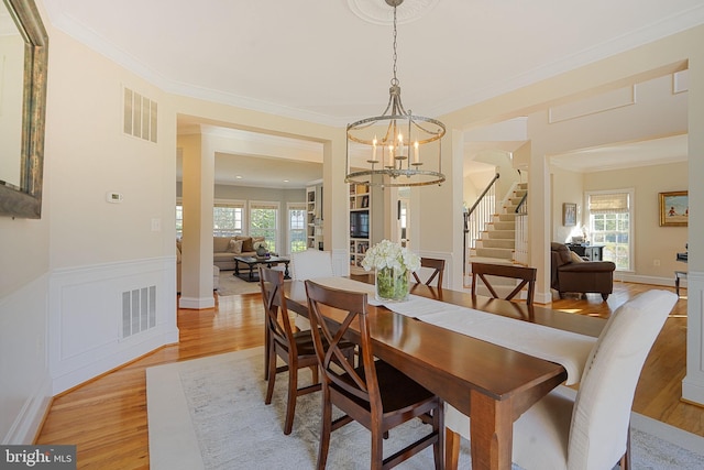 dining area featuring stairway, visible vents, an inviting chandelier, and light wood finished floors
