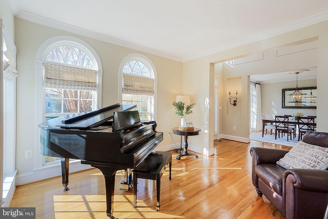 living area featuring crown molding, baseboards, and light wood-type flooring