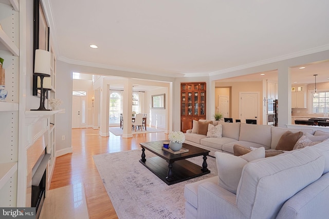 living room featuring a fireplace with flush hearth, light wood-type flooring, baseboards, ornamental molding, and recessed lighting