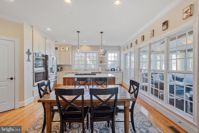 dining area with baseboards, visible vents, ornamental molding, and light wood-type flooring