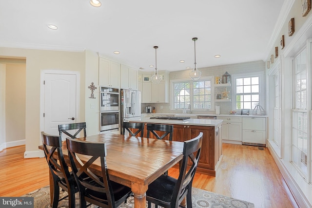 dining space featuring light wood-type flooring, recessed lighting, baseboards, and ornamental molding