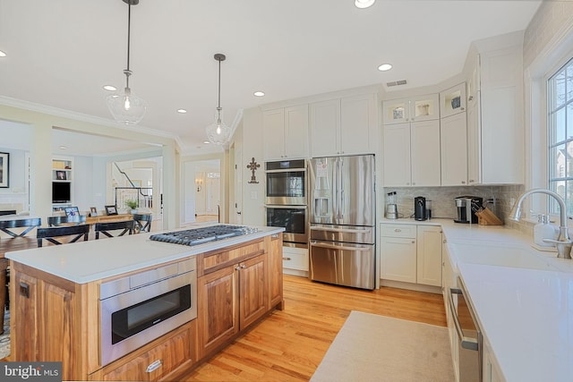 kitchen featuring a sink, light countertops, stainless steel appliances, recessed lighting, and light wood-type flooring