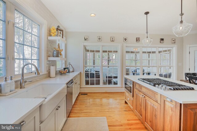 kitchen with open shelves, light wood-style floors, light countertops, stainless steel appliances, and decorative light fixtures