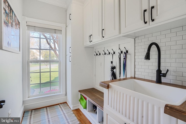 mudroom with a sink, baseboards, a wood stove, and wood finished floors