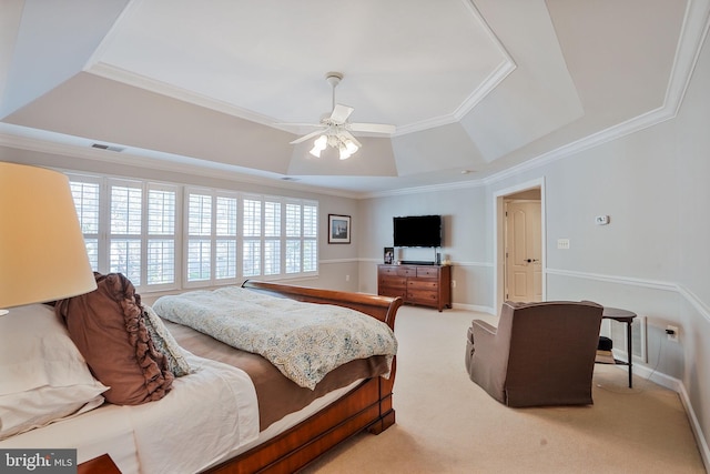 bedroom with a ceiling fan, visible vents, ornamental molding, light carpet, and a tray ceiling