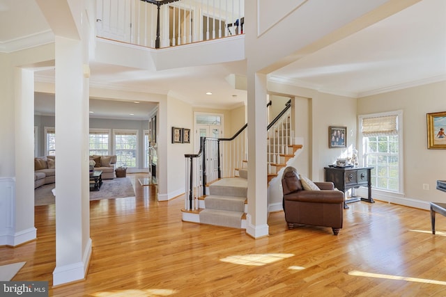 entrance foyer featuring crown molding, baseboards, light wood finished floors, and stairs