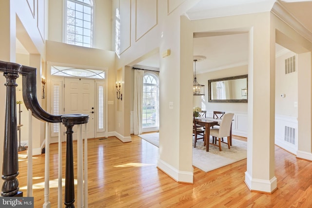 entryway featuring visible vents, crown molding, and light wood-type flooring