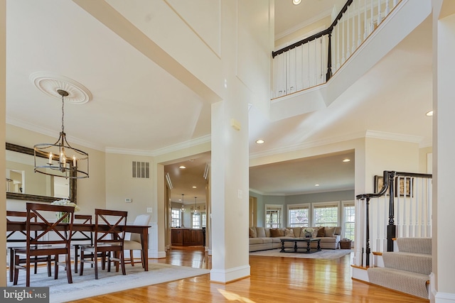 entrance foyer with visible vents, crown molding, wood finished floors, stairway, and a notable chandelier
