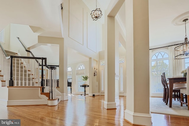 foyer entrance featuring a high ceiling, stairs, wood finished floors, and a chandelier