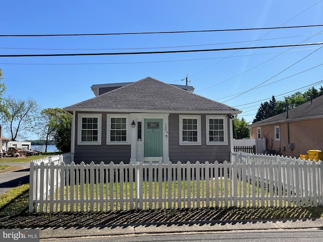 bungalow-style house featuring a fenced front yard and a shingled roof