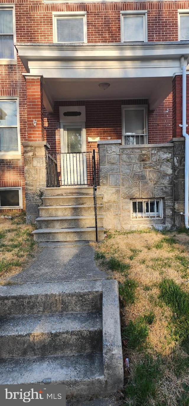 entrance to property featuring brick siding and a porch