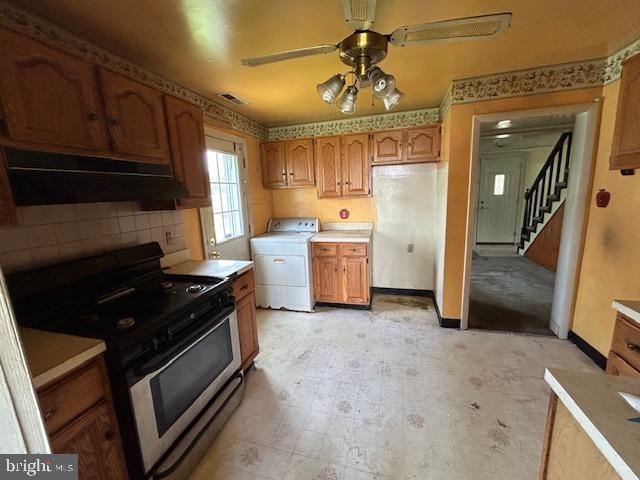 3129 Sollers Point Rd, Baltimore, MD 21222 - kitchen featuring washer / dryer, stainless steel range with electric cooktop, under cabinet range hood, a ceiling fan, and tasteful backsplash