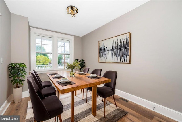 dining space with baseboards, visible vents, and light wood finished floors