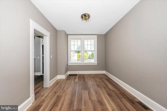 spare room featuring baseboards, visible vents, and wood finished floors