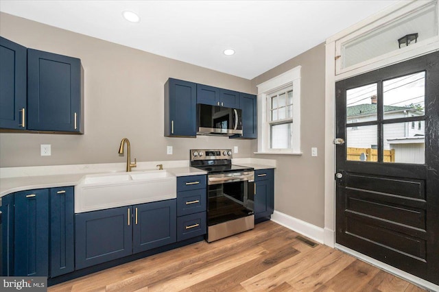 kitchen featuring stainless steel appliances, blue cabinetry, visible vents, and a sink