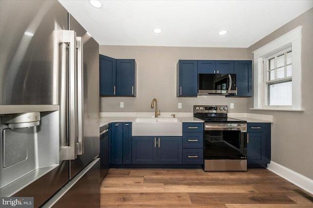 kitchen featuring a sink, appliances with stainless steel finishes, and blue cabinetry