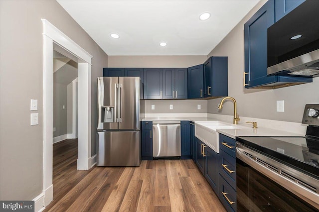 kitchen featuring a sink, light countertops, light wood-style flooring, stainless steel appliances, and blue cabinets