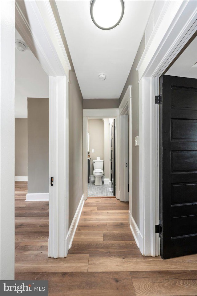 corridor with baseboards and wood finished floors