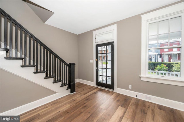 foyer with stairs, baseboards, plenty of natural light, and wood finished floors