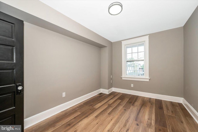 spare room featuring baseboards and wood finished floors