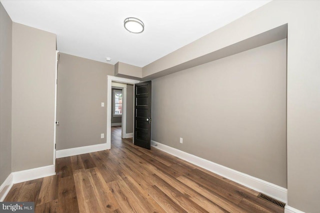unfurnished room featuring baseboards, visible vents, and wood finished floors