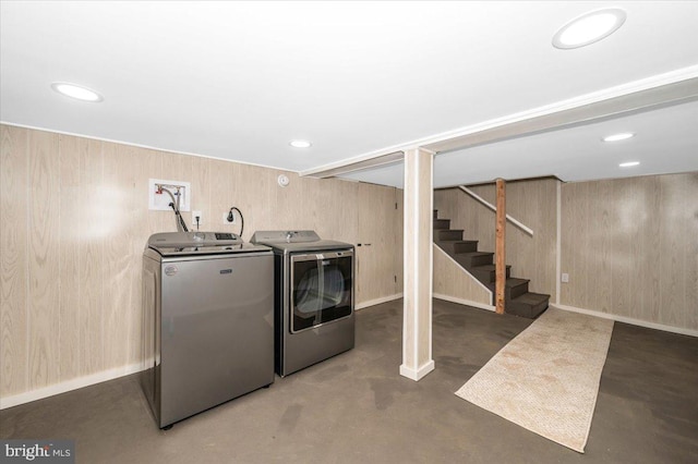 clothes washing area with laundry area, wood walls, baseboards, and independent washer and dryer
