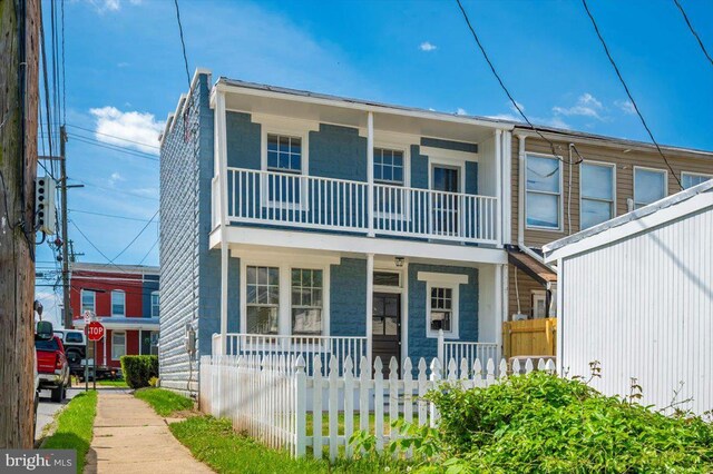 townhome / multi-family property with a porch, fence private yard, and a balcony