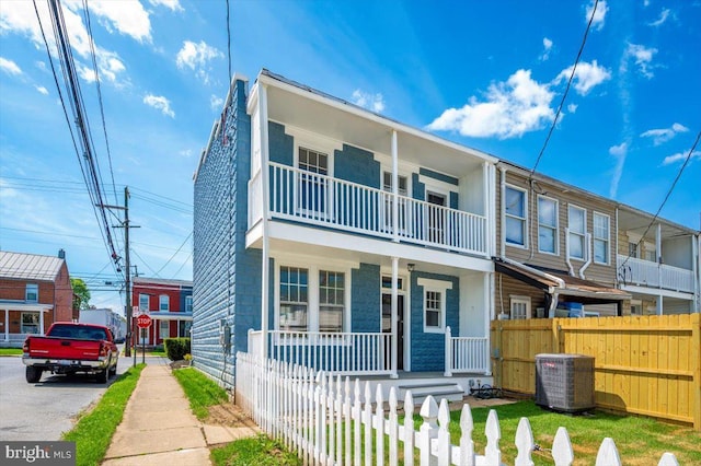 multi unit property with central air condition unit, fence private yard, a porch, and a balcony