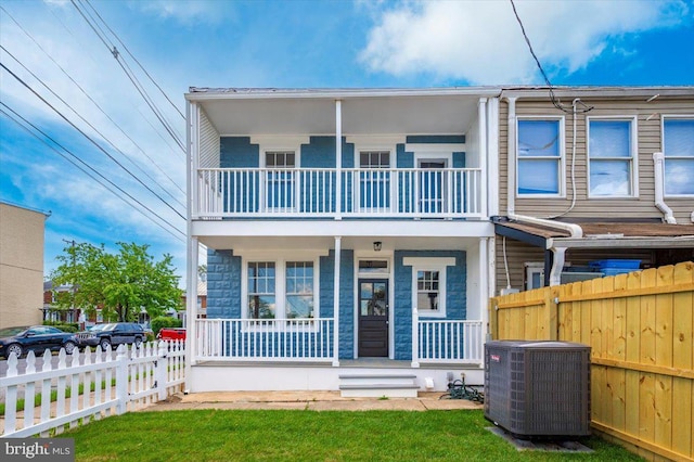 view of property featuring fence private yard, central AC, a balcony, and covered porch