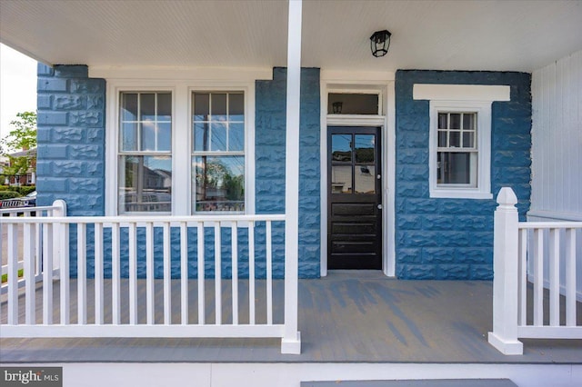 property entrance featuring covered porch and stone siding