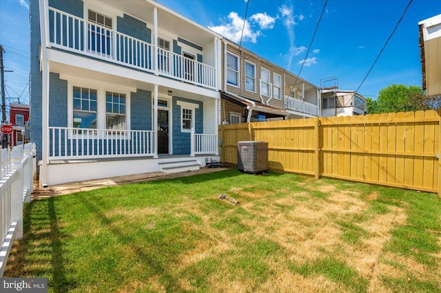 back of house with a lawn, central AC, and a fenced backyard