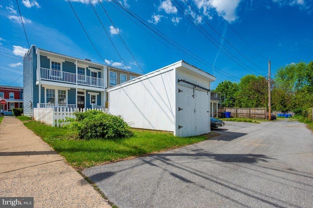 exterior space featuring fence, an outbuilding, a shed, and a balcony
