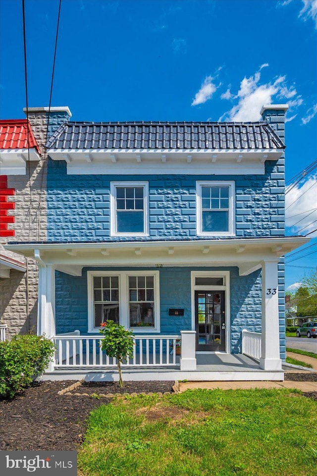 view of front of home with a chimney, a porch, and stone siding