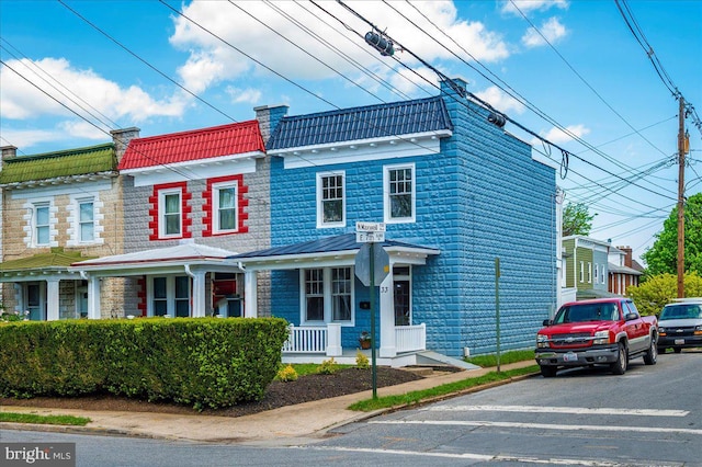 view of front facade featuring a chimney and a porch