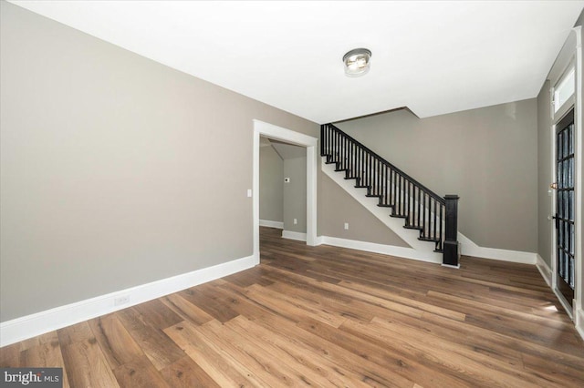 foyer with baseboards, wood finished floors, and stairway