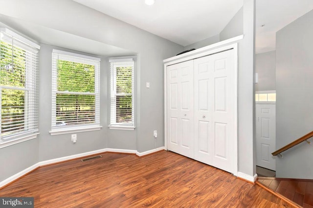 unfurnished bedroom with baseboards, a closet, visible vents, and wood finished floors