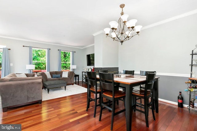 dining area featuring crown molding, wood finished floors, baseboards, and a notable chandelier