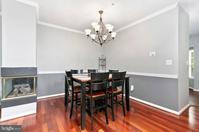 dining area with crown molding, a notable chandelier, baseboards, and wood finished floors