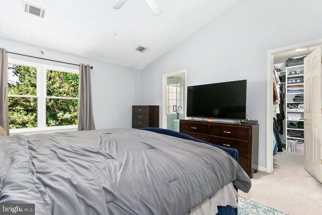 bedroom with vaulted ceiling, a walk in closet, light carpet, and visible vents