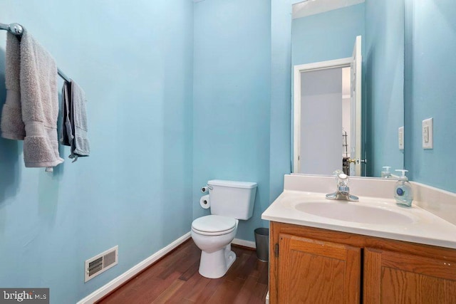 bathroom with toilet, wood finished floors, visible vents, baseboards, and vanity