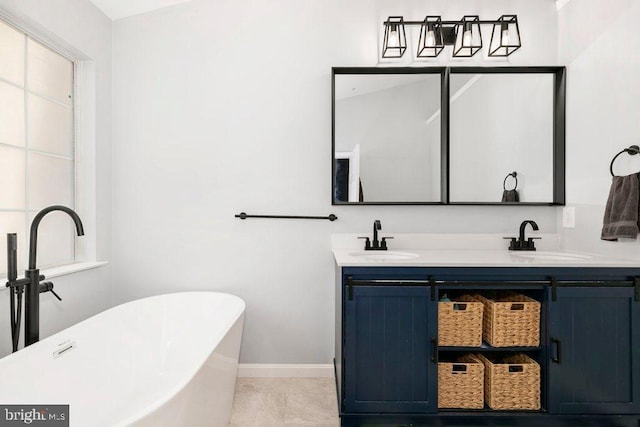 bathroom with baseboards, a freestanding tub, double vanity, and a sink