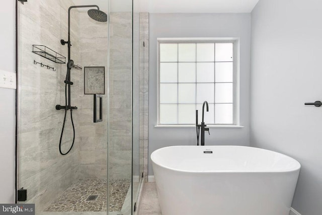 bathroom featuring baseboards, a shower stall, and a freestanding tub