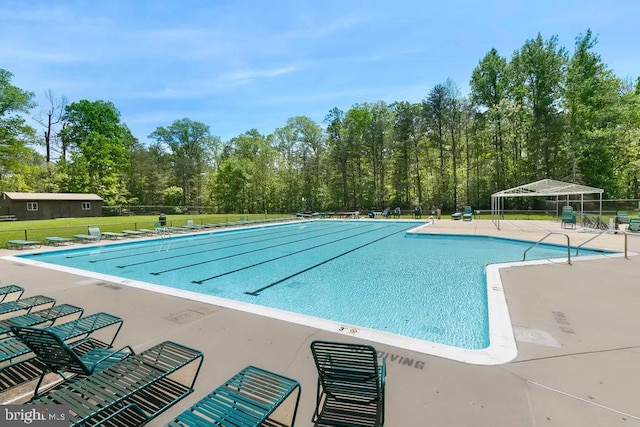 community pool with a patio area, fence, and a lawn
