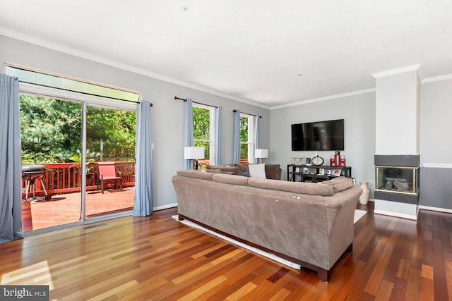 living area with baseboards, a multi sided fireplace, visible vents, crown molding, and wood finished floors
