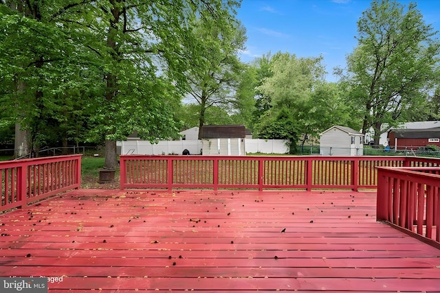 wooden terrace featuring a storage unit, a fenced backyard, and an outdoor structure